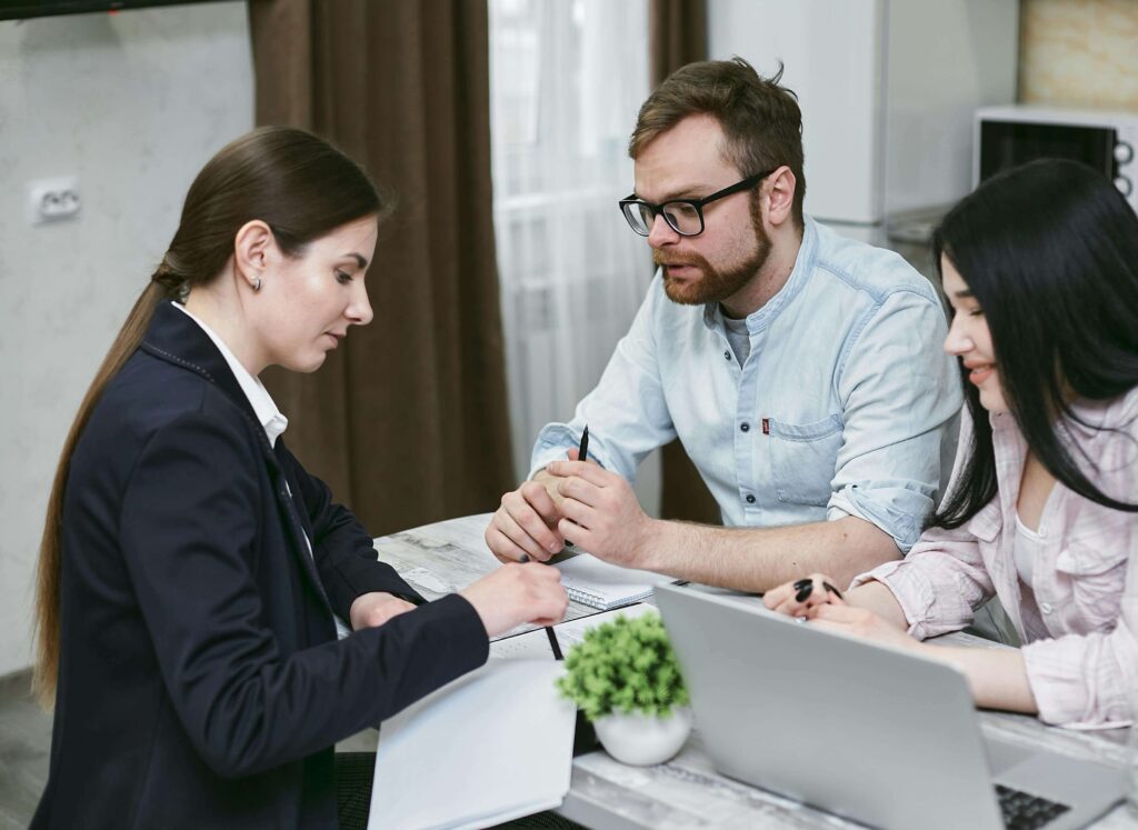 Female staff member attending to two customers in a professional office setting at GCFDL